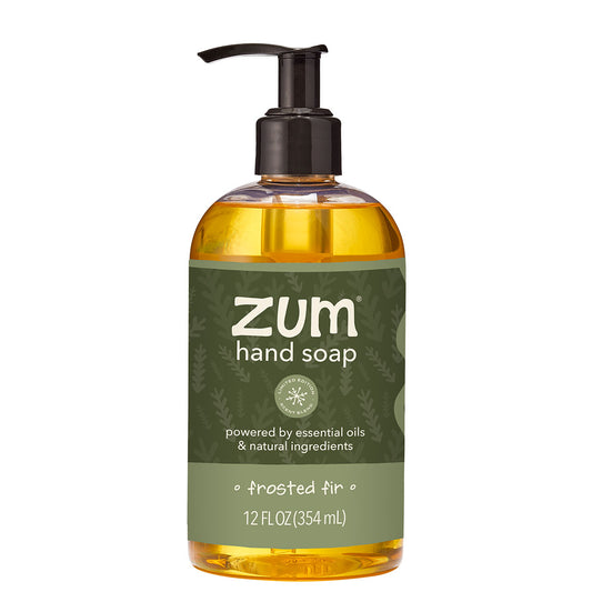 A 12 fl oz bottle of Zum Hand Soap in the frosted fig scent, featuring a dark olive green label and a black pump dispenser, filled with amber-colored liquid, on a solid white background.