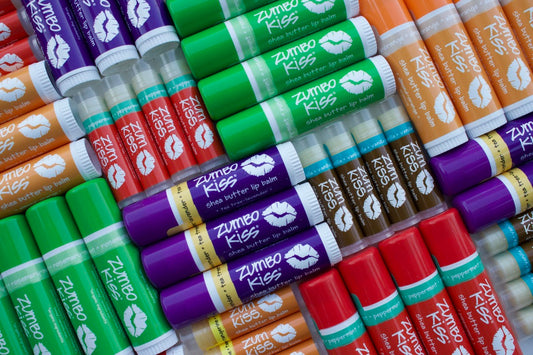 Group shot of various scents and sizes of Zum Kiss lip balm.