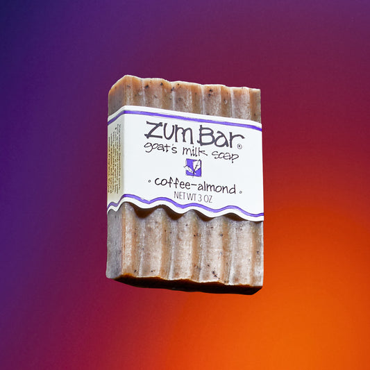 Labeled Coffee-Almond bar soap flying in the air with a purple to orange gradient background.