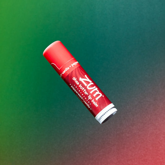 Peppermint-Vanilla flavored 0.5 oz Lip Balm tube flying in the air with a green to red gradient background.