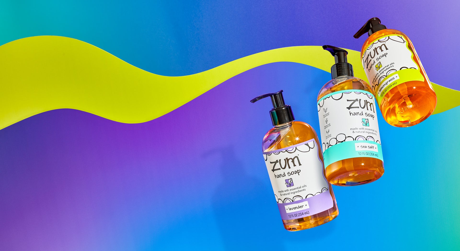 Lavender, Sea Salt, and Lemongrass Hand Soap bottles with pumps flying in the air with a background consisting of a purple to blue gradient wave, a lime green wave behind it, and blue to purple gradient behind both.